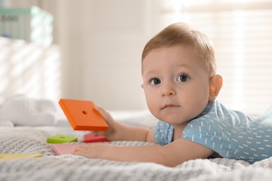 Photo of Cute little baby with toys on bed at home