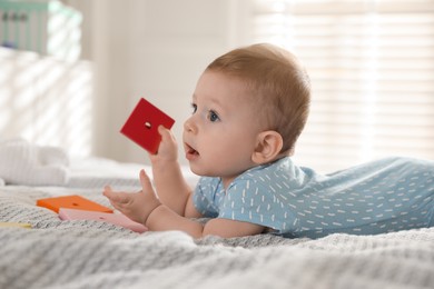 Photo of Cute little baby with toys on bed at home