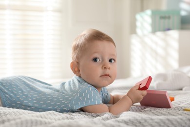 Photo of Cute little baby with toys on bed at home