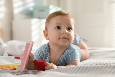 Photo of Cute little baby with toys on bed at home