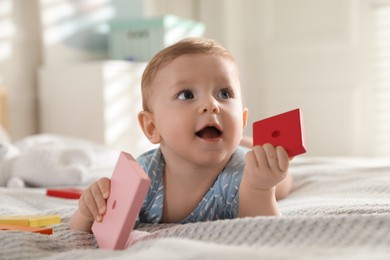 Photo of Cute little baby with toys on bed at home