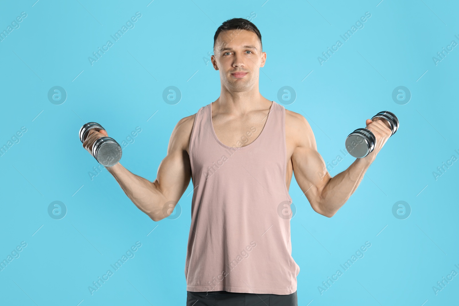 Photo of Man exercising with dumbbells on light blue background