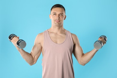 Photo of Man exercising with dumbbells on light blue background