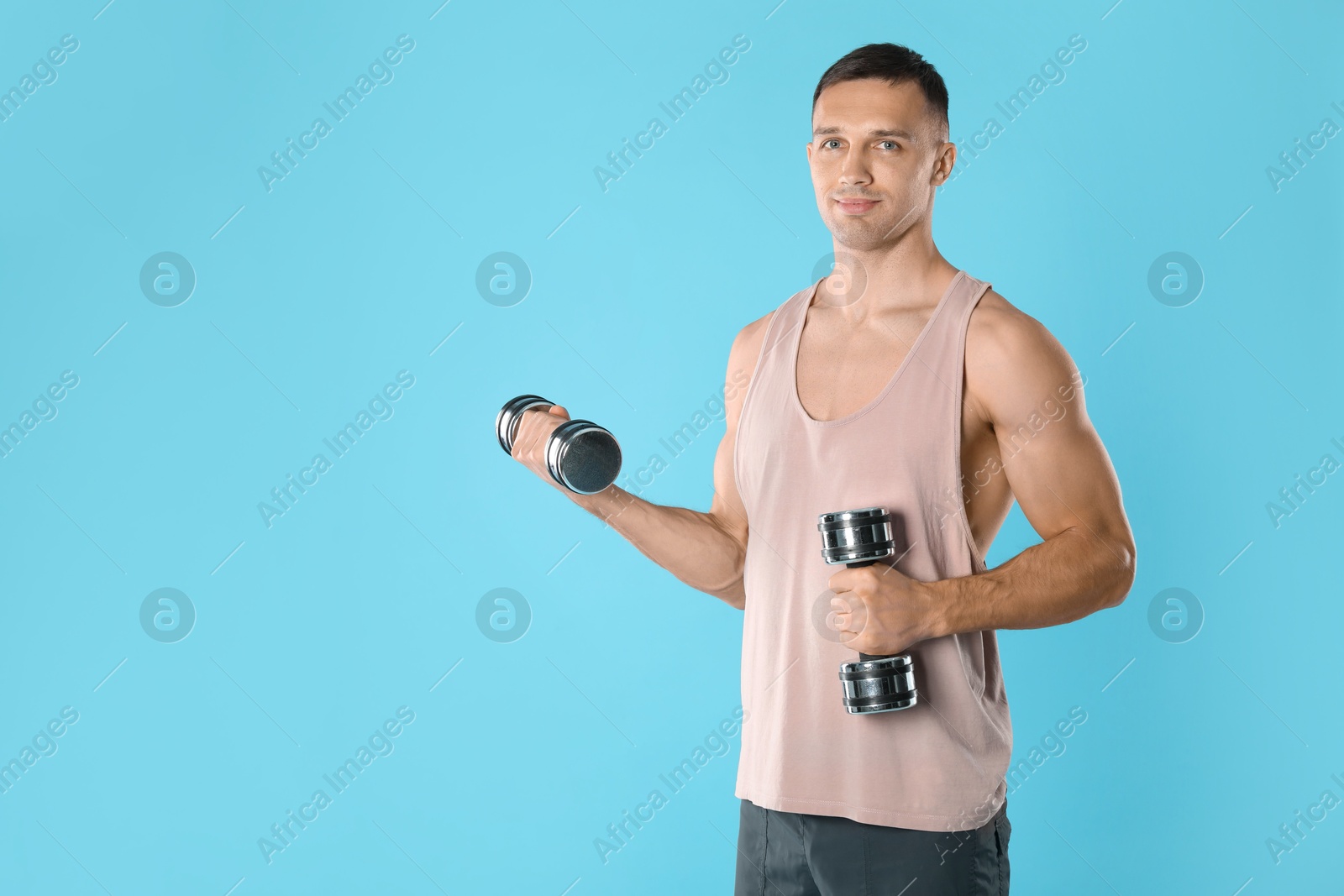 Photo of Man exercising with dumbbells on light blue background, space for text