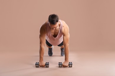 Photo of Man exercising with dumbbells on light brown background