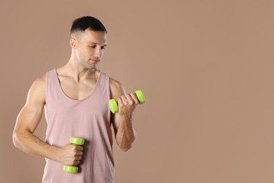 Photo of Man exercising with dumbbells on light brown background, space for text