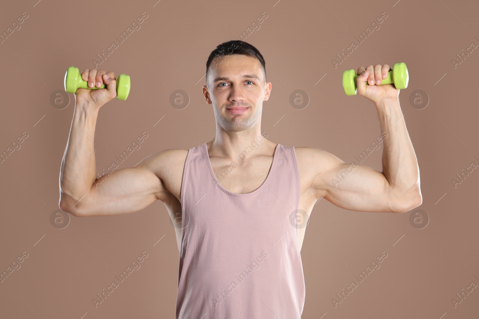 Photo of Man exercising with dumbbells on light brown background