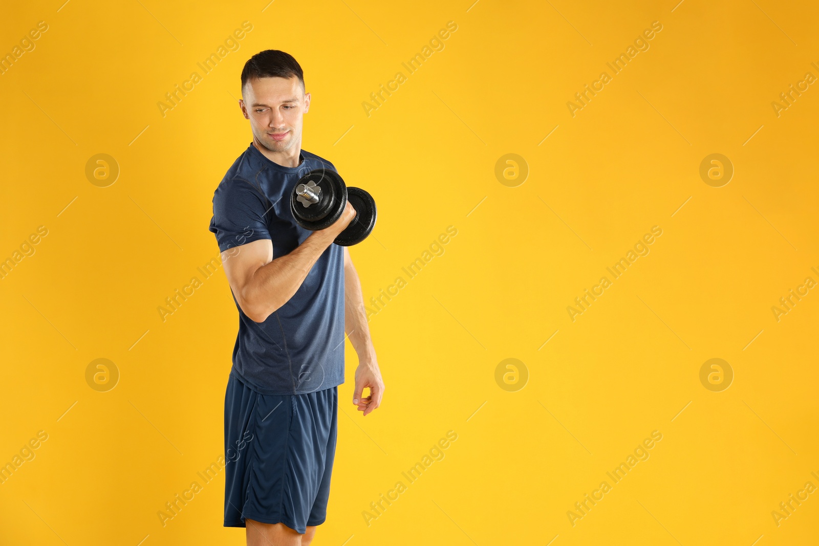 Photo of Man exercising with barbell on yellow background, space for text