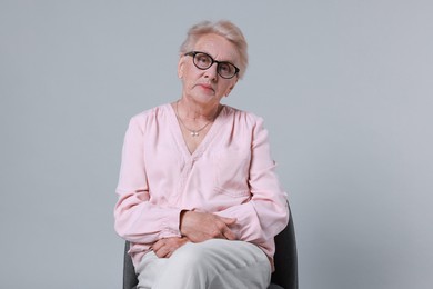 Photo of Senior woman on chair against light background