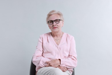 Photo of Senior woman on chair against light background