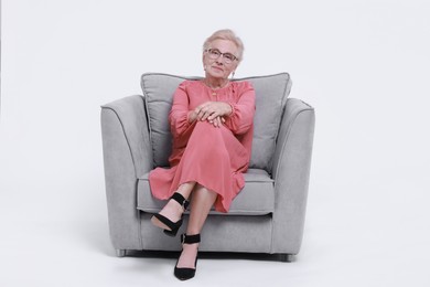 Photo of Senior woman in armchair against white background