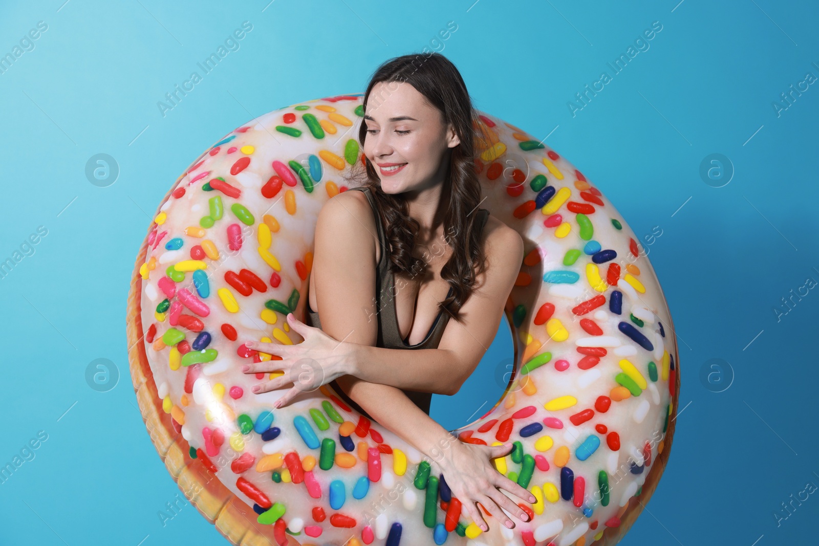 Photo of Beautiful woman in swimsuit with inflatable ring on light blue background