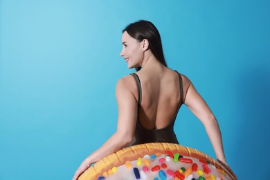 Photo of Beautiful woman in swimsuit with inflatable ring on light blue background