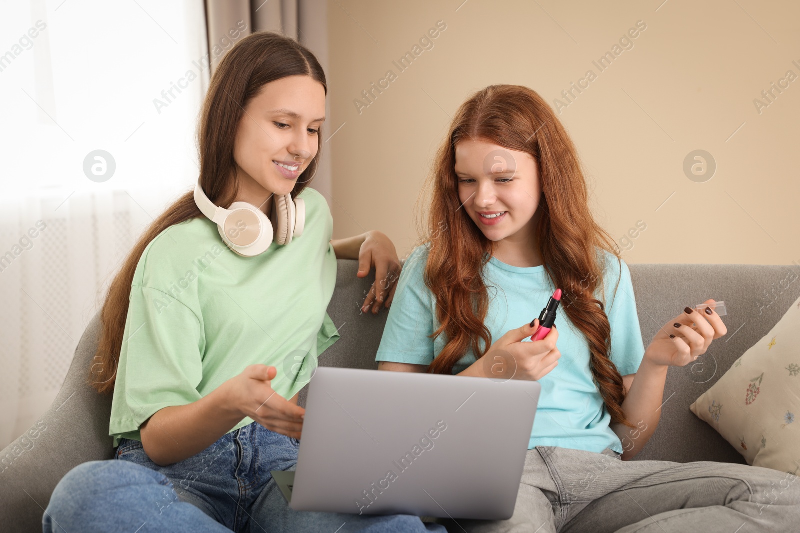 Photo of Teenage girls with laptop applying makeup products indoors