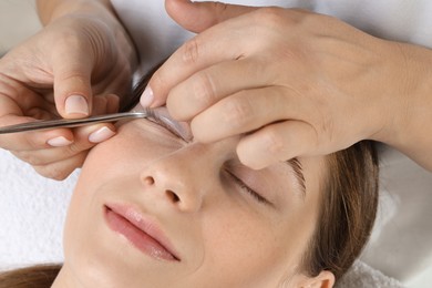 Photo of Eyelash lamination procedure. Esthetician placing silicone pad on woman's eyelid in beauty salon, closeup