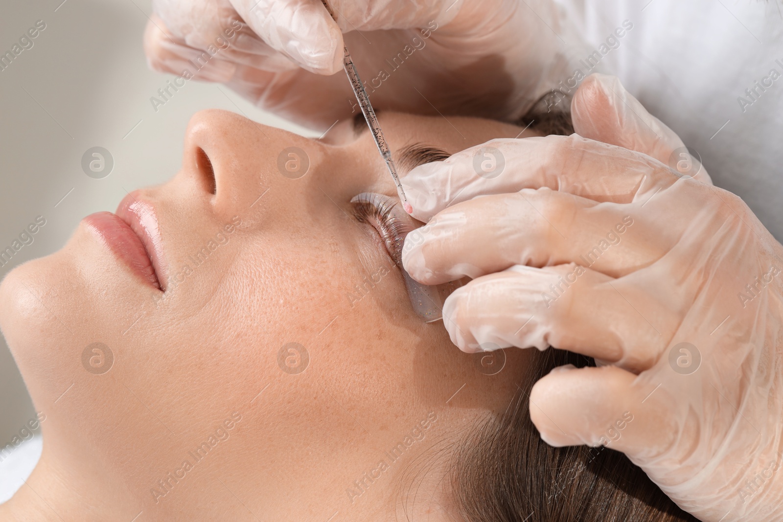 Photo of Eyelash lamination procedure. Esthetician sticking woman's lashes to pad in beauty salon, closeup