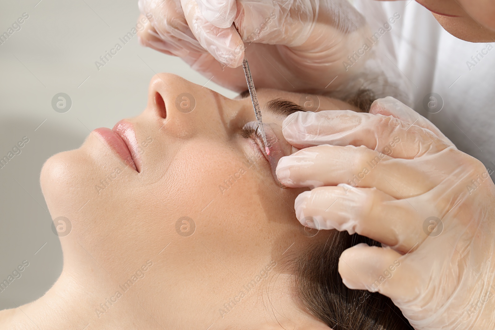 Photo of Eyelash lamination procedure. Esthetician sticking woman's lashes to pad in beauty salon, closeup