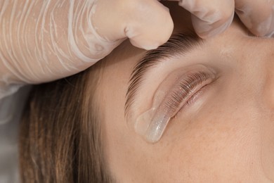 Woman undergoing eyelash laminating procedure in beauty salon, closeup