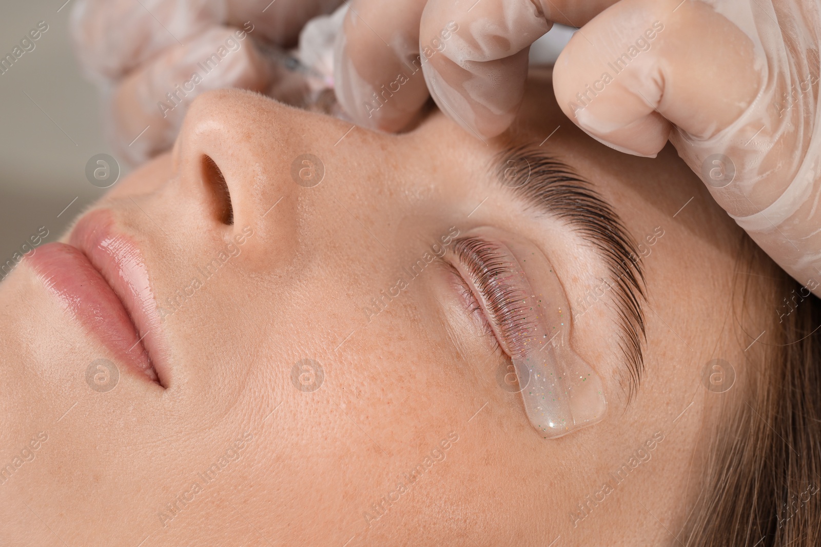 Photo of Woman undergoing eyelash laminating procedure in beauty salon, closeup