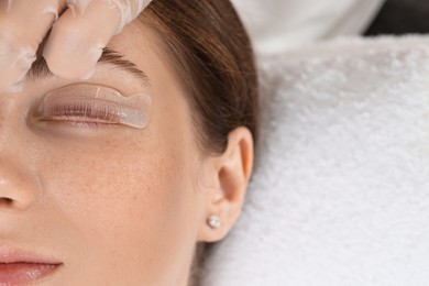 Photo of Woman undergoing eyelash laminating procedure in beauty salon, closeup