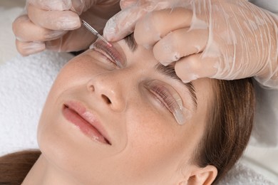 Photo of Eyelash lamination procedure. Esthetician sticking woman's lashes to pad in beauty salon, closeup