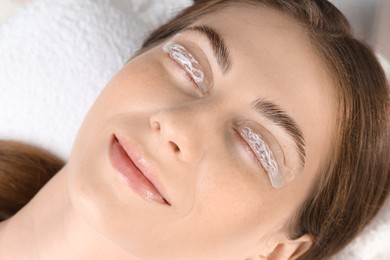 Photo of Woman undergoing eyelash laminating procedure in beauty salon, closeup