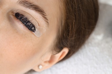 Woman undergoing eyelash laminating and tinting procedure in beauty salon, closeup