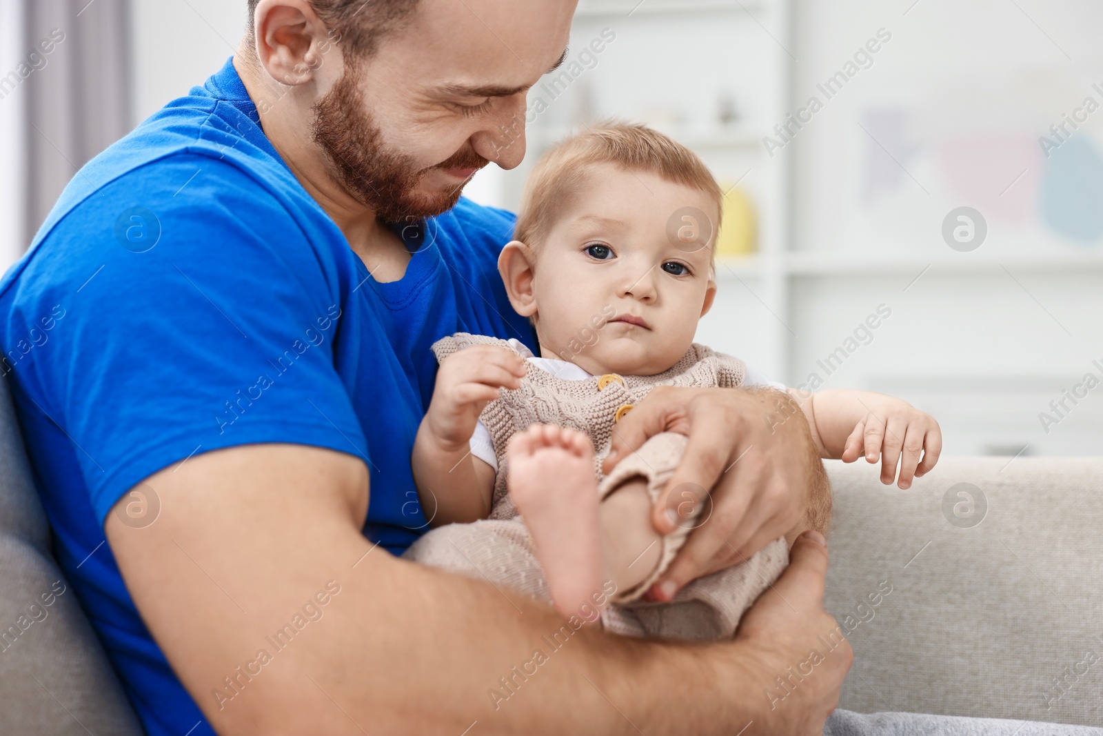 Photo of Father with his little baby on sofa at home