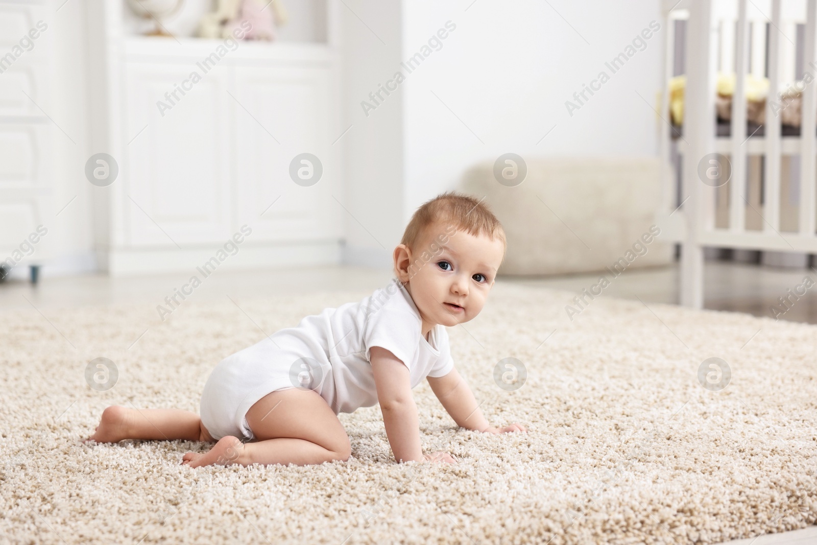 Photo of Adorable baby crawling on floor in nursery