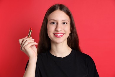 Photo of Smiling teenage girl with lipstick on red background