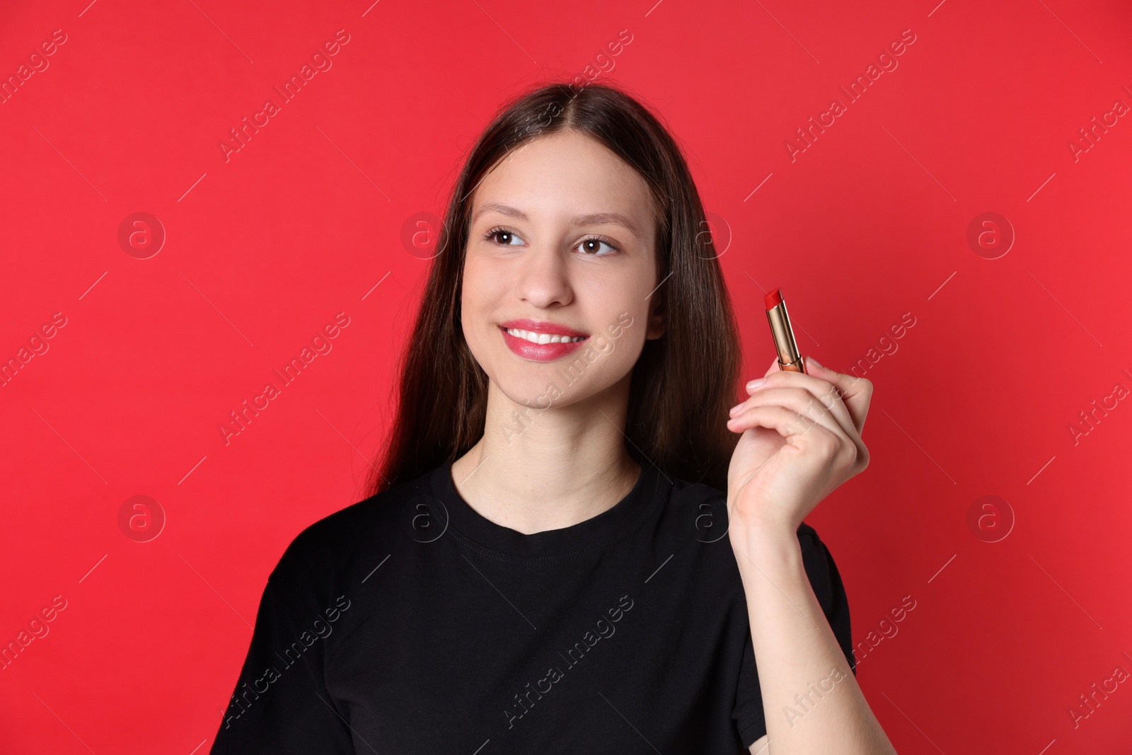 Photo of Smiling teenage girl with lipstick on red background