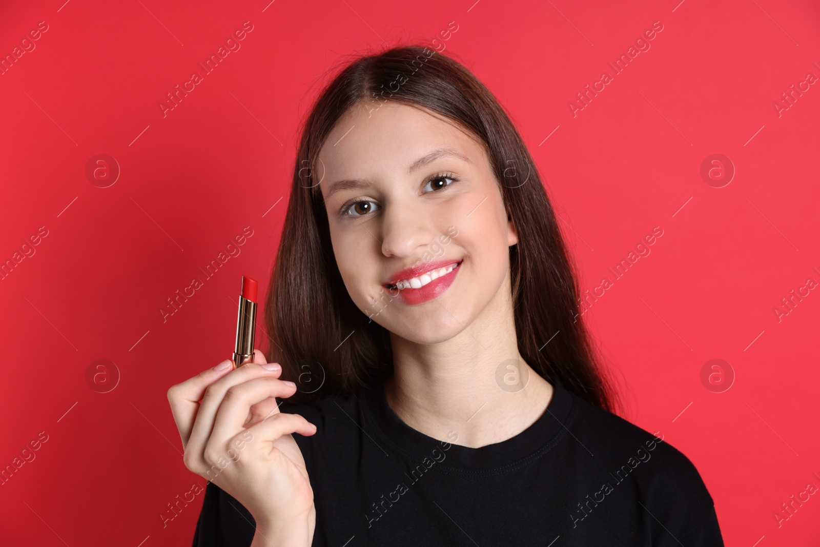 Photo of Smiling teenage girl with lipstick on red background