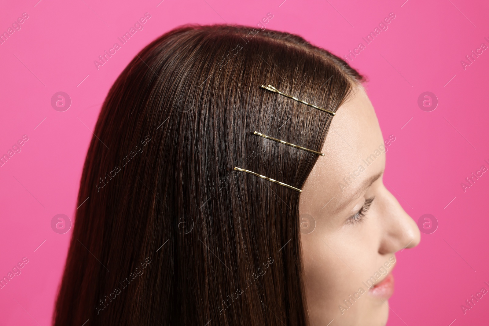 Photo of Teenage girl with stylish hair clips on pink background, closeup