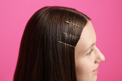 Photo of Teenage girl with stylish hair clips on pink background, closeup