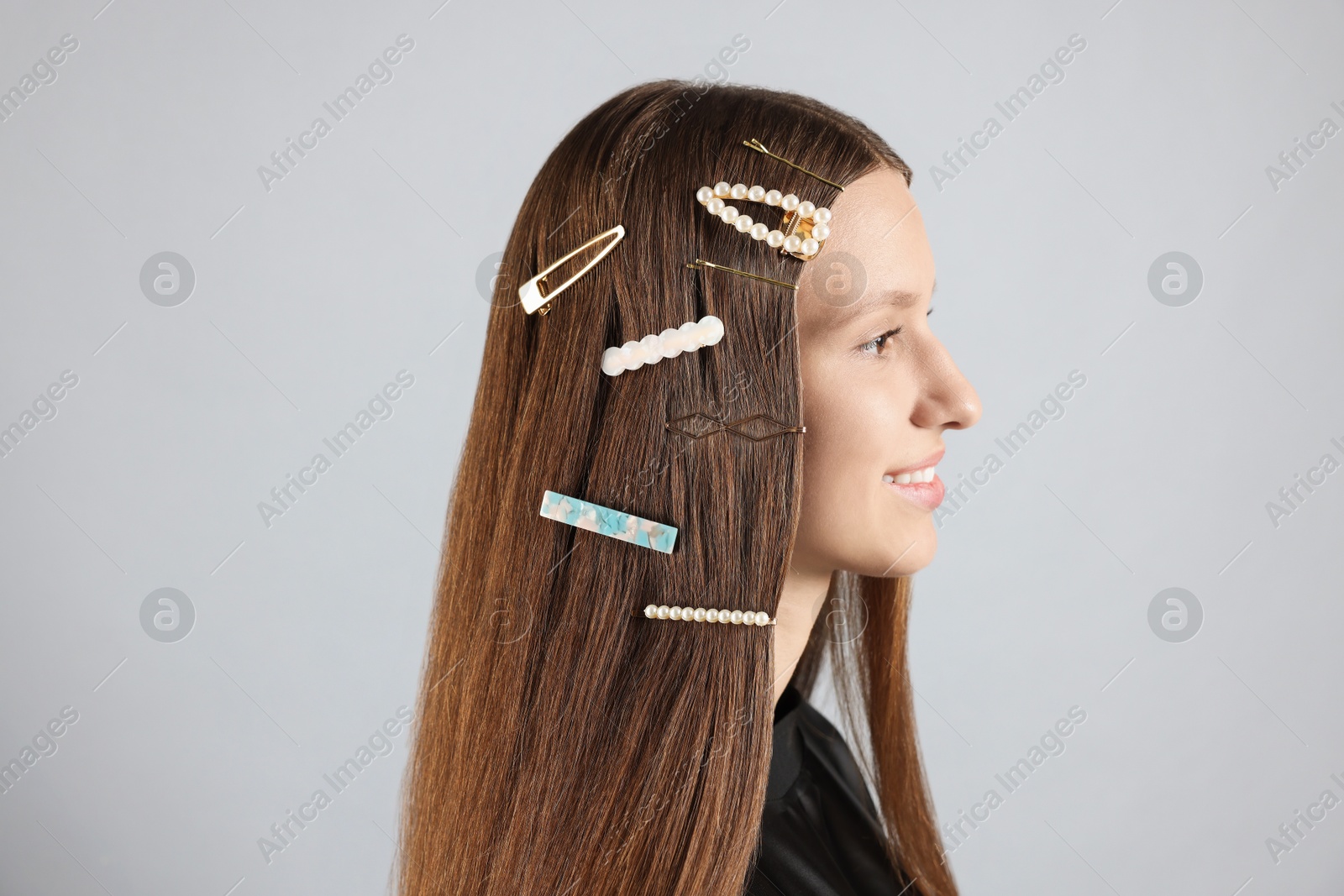 Photo of Teenage girl with stylish hair clips on light grey background, closeup