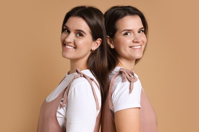 Portrait of happy twin sisters on pale brown background