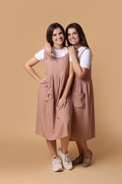 Portrait of happy twin sisters on pale brown background