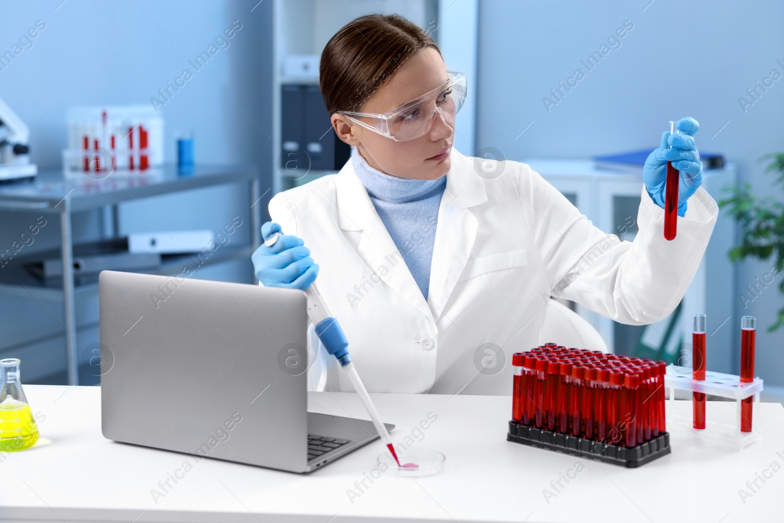 Photo of Laboratory testing. Doctor holding test tube with blood sample at table indoors