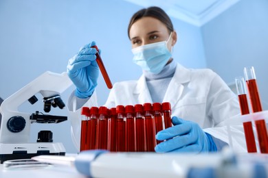 Laboratory testing. Doctor taking test tube with blood sample at table indoors, low angle view