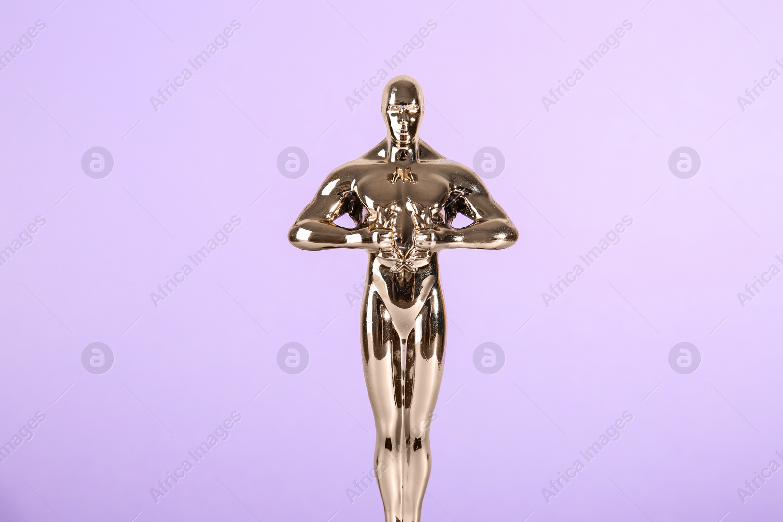 Photo of Golden trophy in shape of human figure on violet background