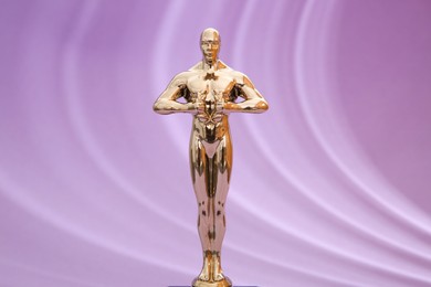 Photo of Golden trophy in shape of human figure on violet background