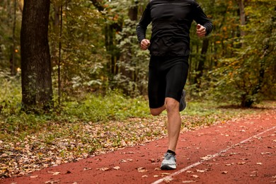 Photo of Athletic man running in park, closeup. Space for text