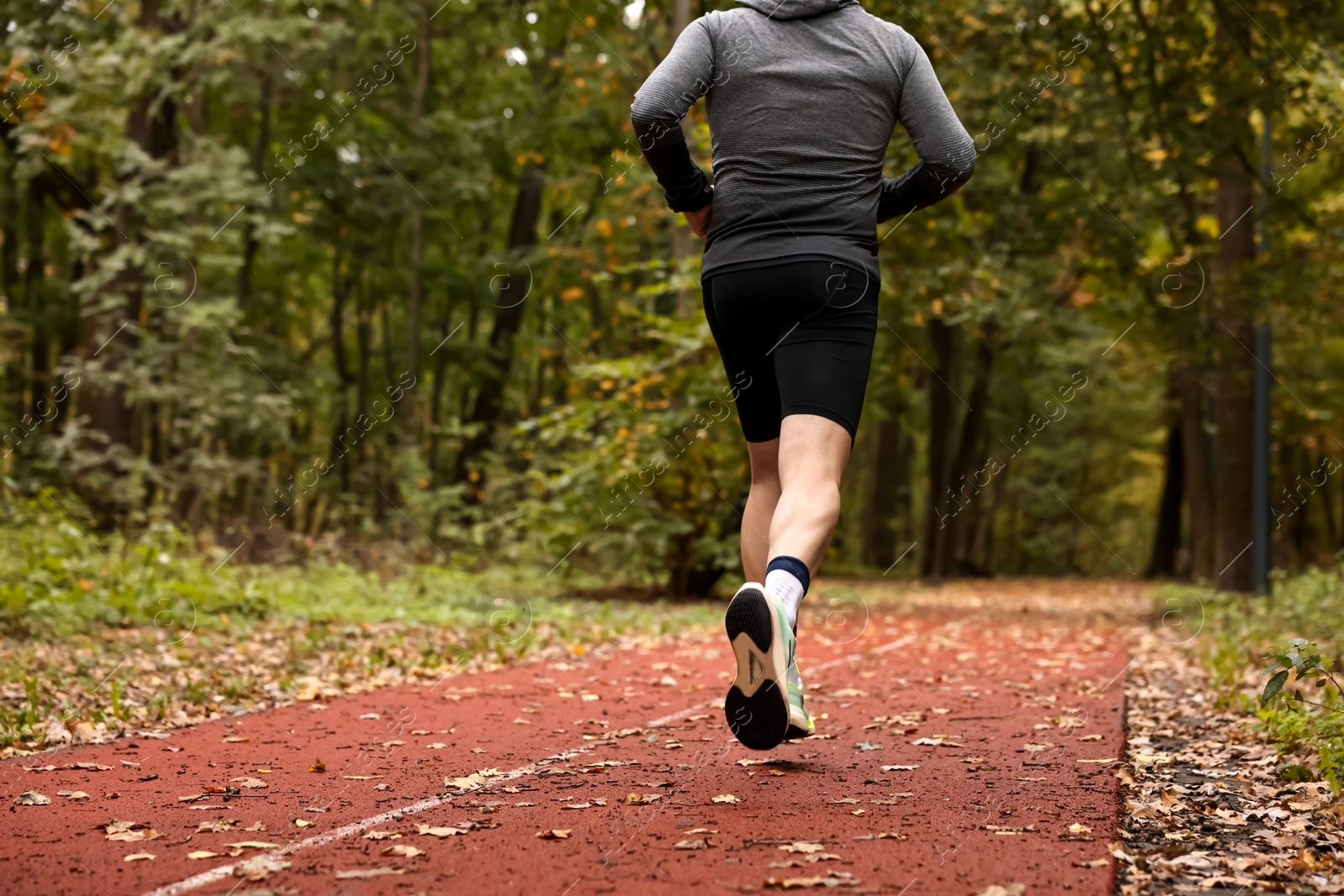 Photo of Athletic man running in park, closeup. Healthy lifestyle