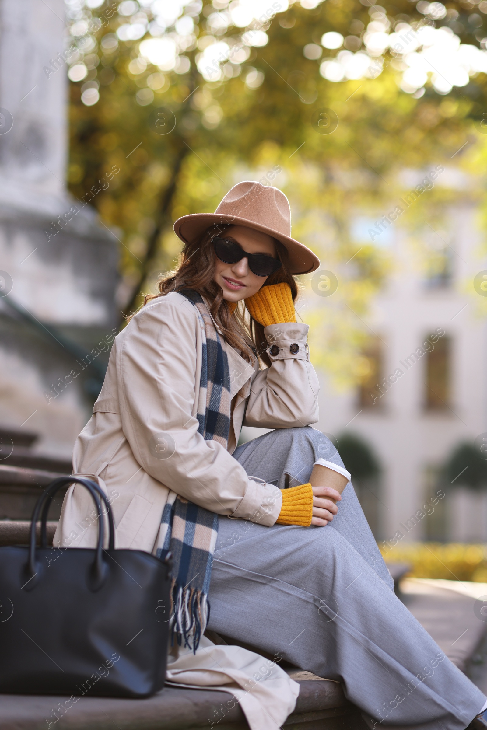 Photo of Charming young woman with cup of coffee on city street. Autumn season