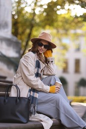 Photo of Charming young woman with cup of coffee on city street. Autumn season