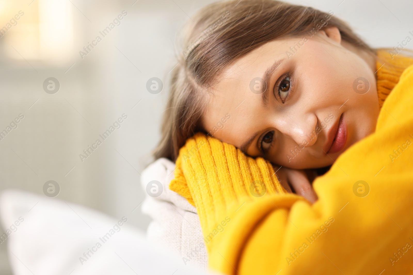 Photo of Charming young woman on sofa at home, space for text. Autumn atmosphere