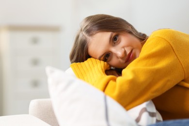 Photo of Charming young woman on sofa at home, space for text. Autumn atmosphere