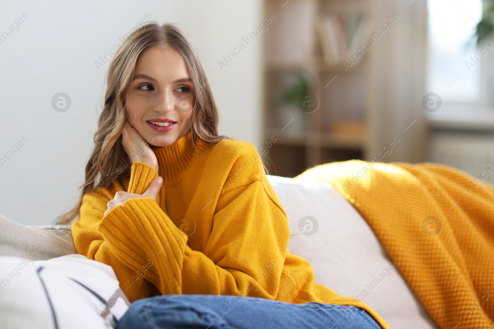 Photo of Charming young woman on sofa at home. Autumn atmosphere