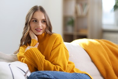 Photo of Charming young woman on sofa at home. Autumn atmosphere