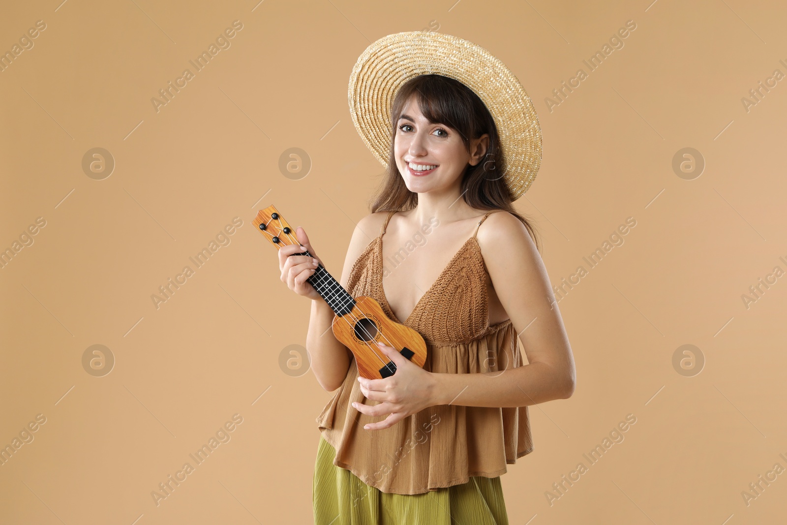 Photo of Happy woman playing ukulele on beige background